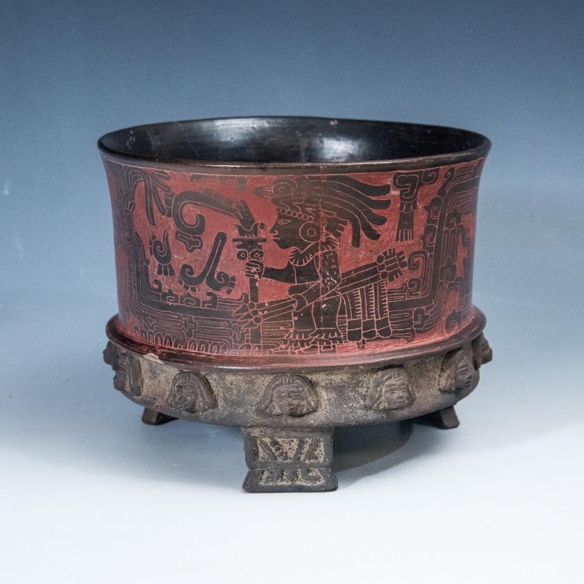 2087   -  ARQUEOLOGÍA. PREHISPÁNICO. Teotihuacán. Vaso trípode con decoración geométrica y antropomorfa incisa; en la parte inferior, orla de rostros humanos aplicada (ca. 100 a. C.- 650 d. C.) Cerámica policromada. Altura 12,5 cm.